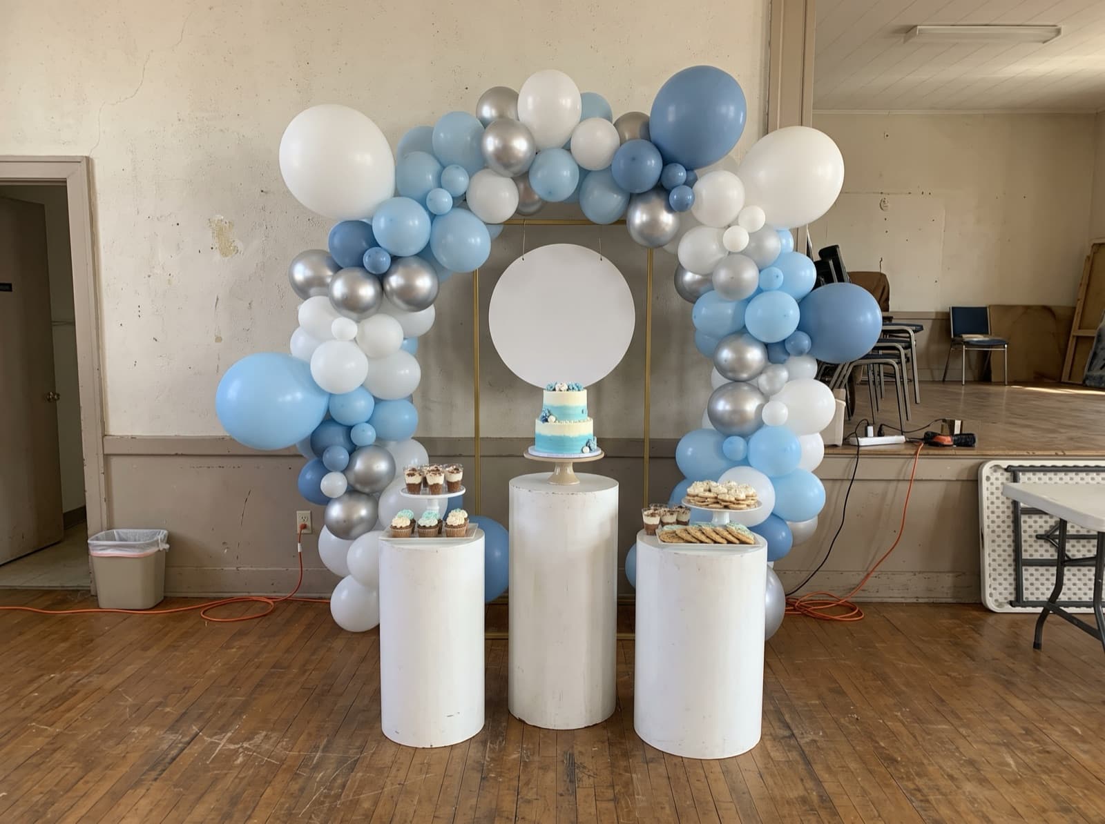 Balloon backdrop with white pedestals holding desserts