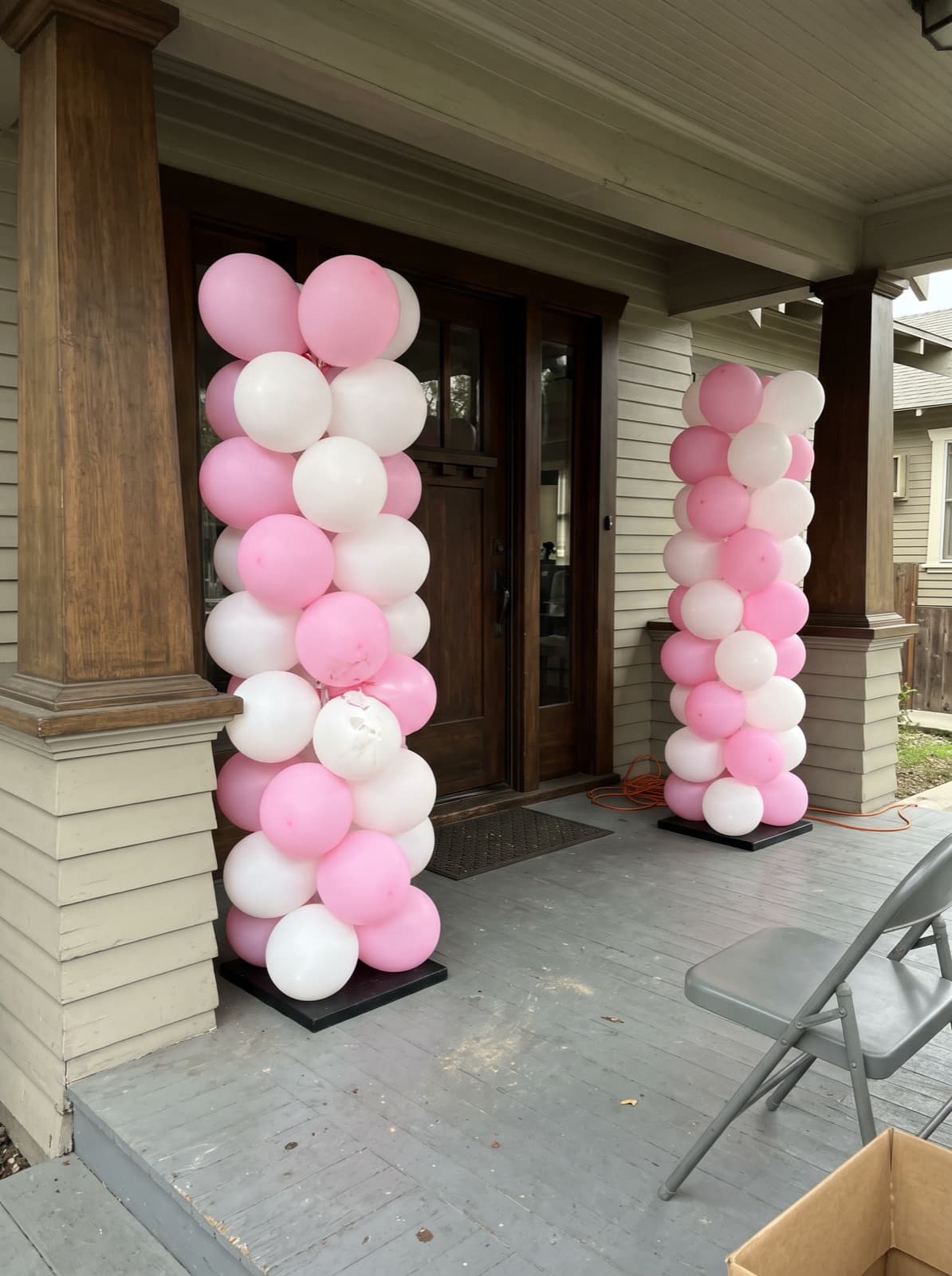 Pink and white balloon columns at a craftsman porch