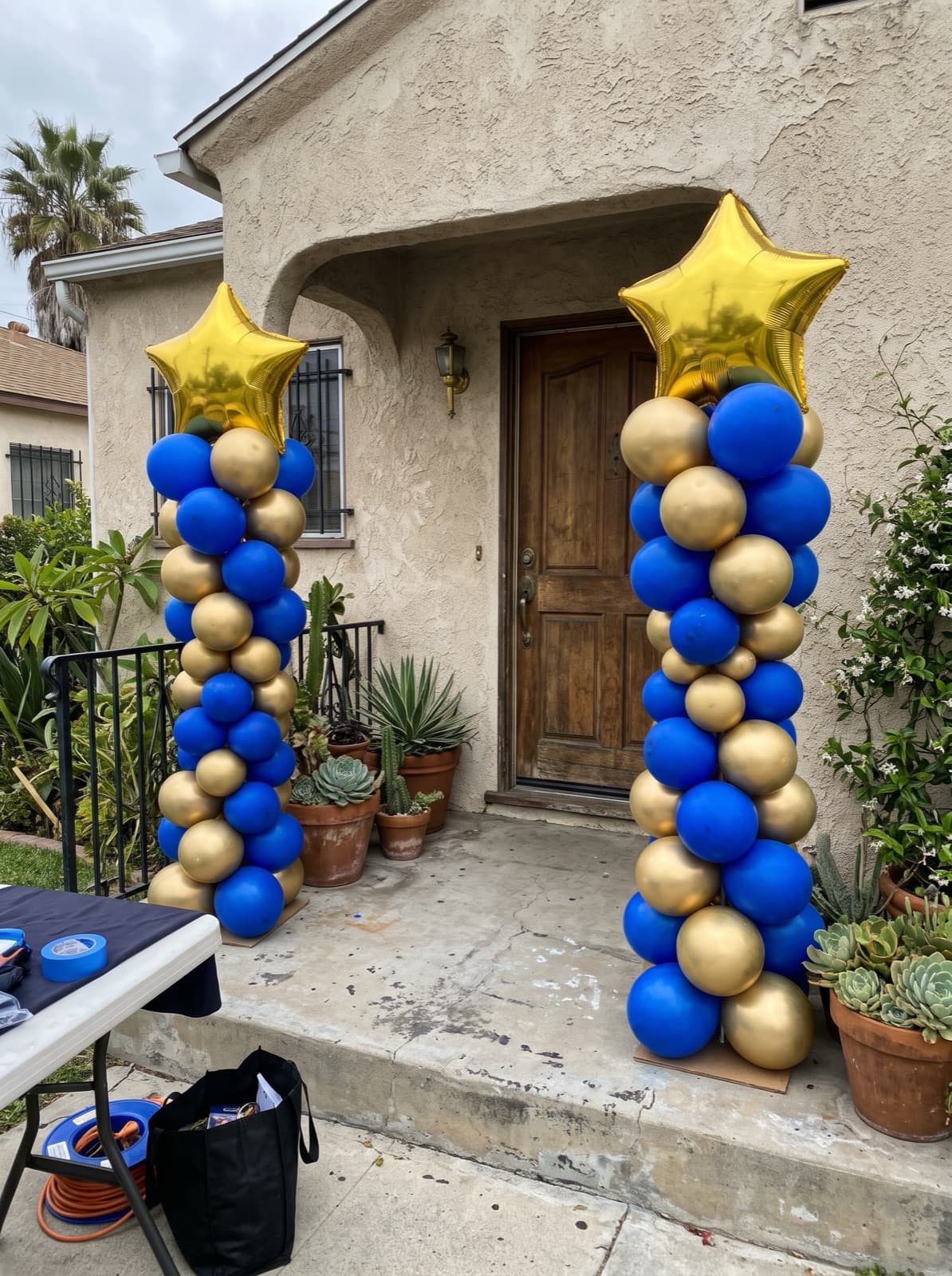 Pair of spiral balloon columns in blue and gold with star toppers at a Los Angeles graduation party