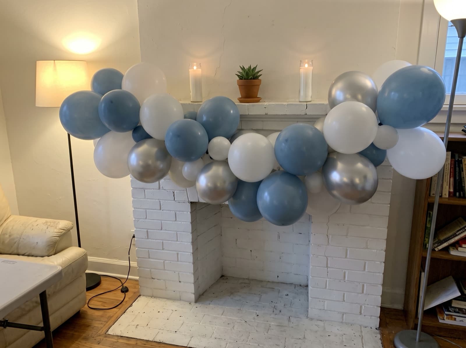 Organic balloon garland in dusty blue, white and silver along a fireplace mantel in a Los Angeles home
