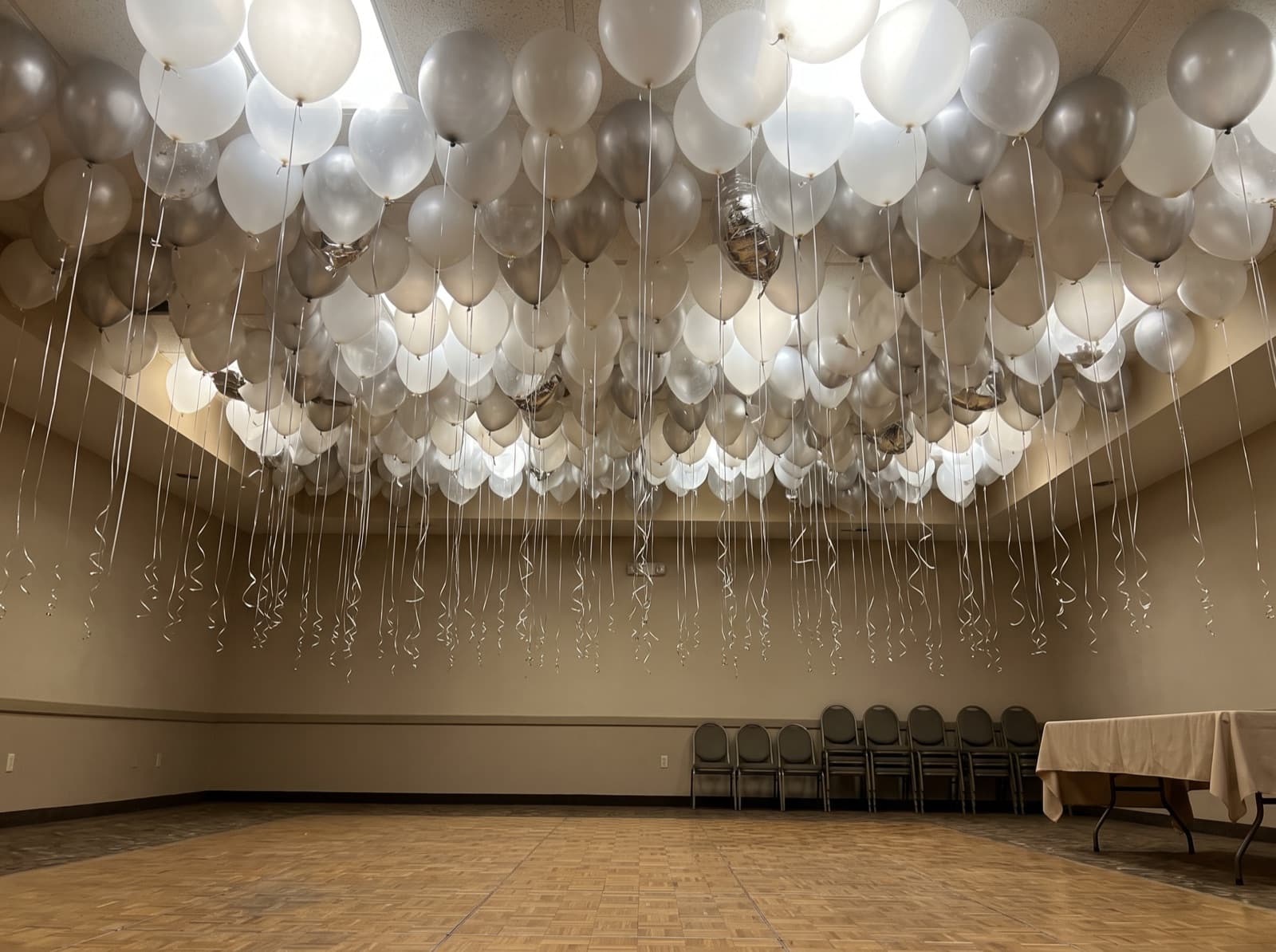 White, clear and silver balloon ceiling above a ballroom floor