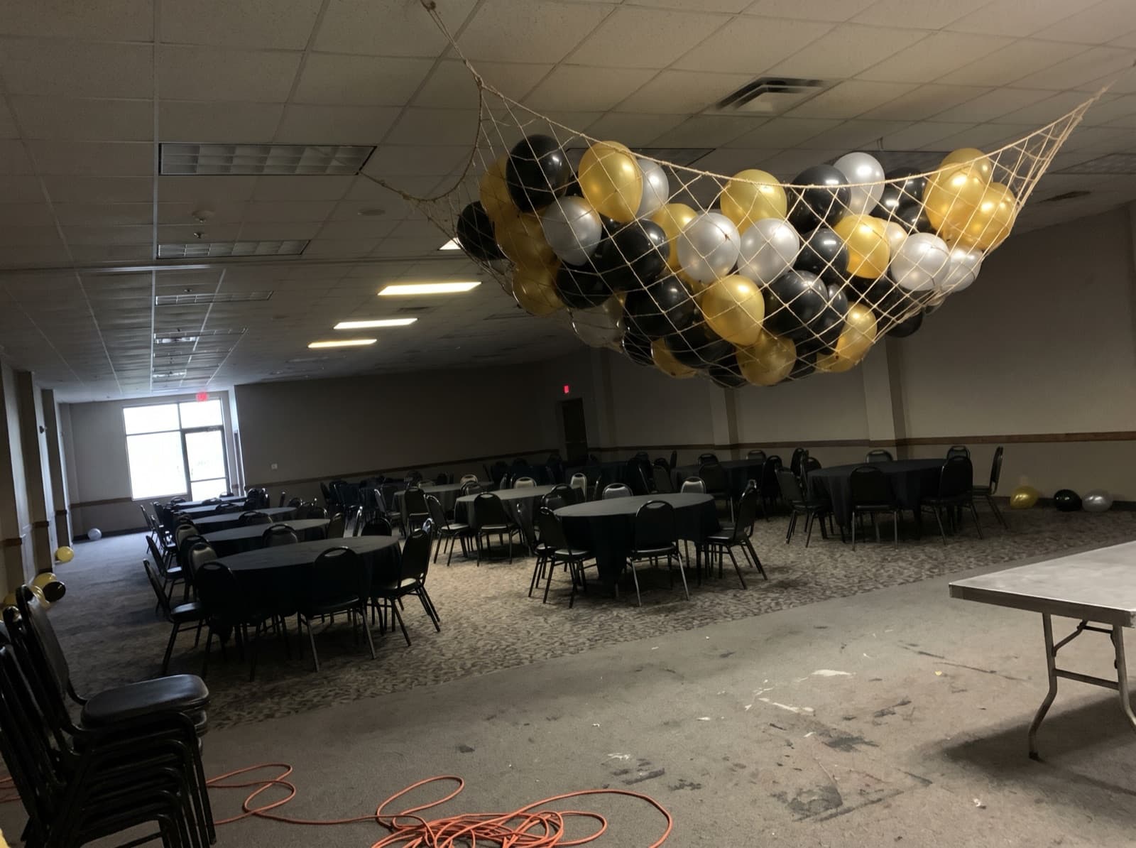 Gold, silver and black balloons waiting in a drop net