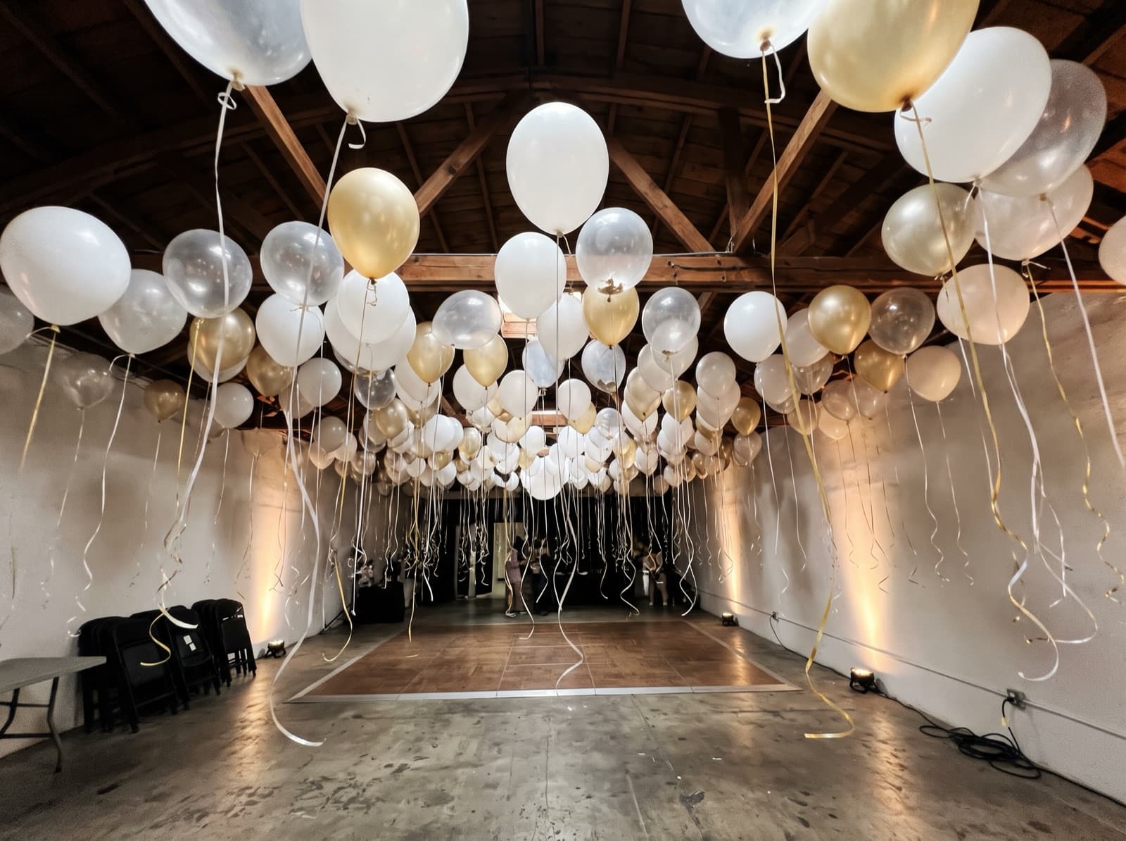 Balloon ceiling of white, clear and champagne balloons over a dance floor in a Los Angeles event space