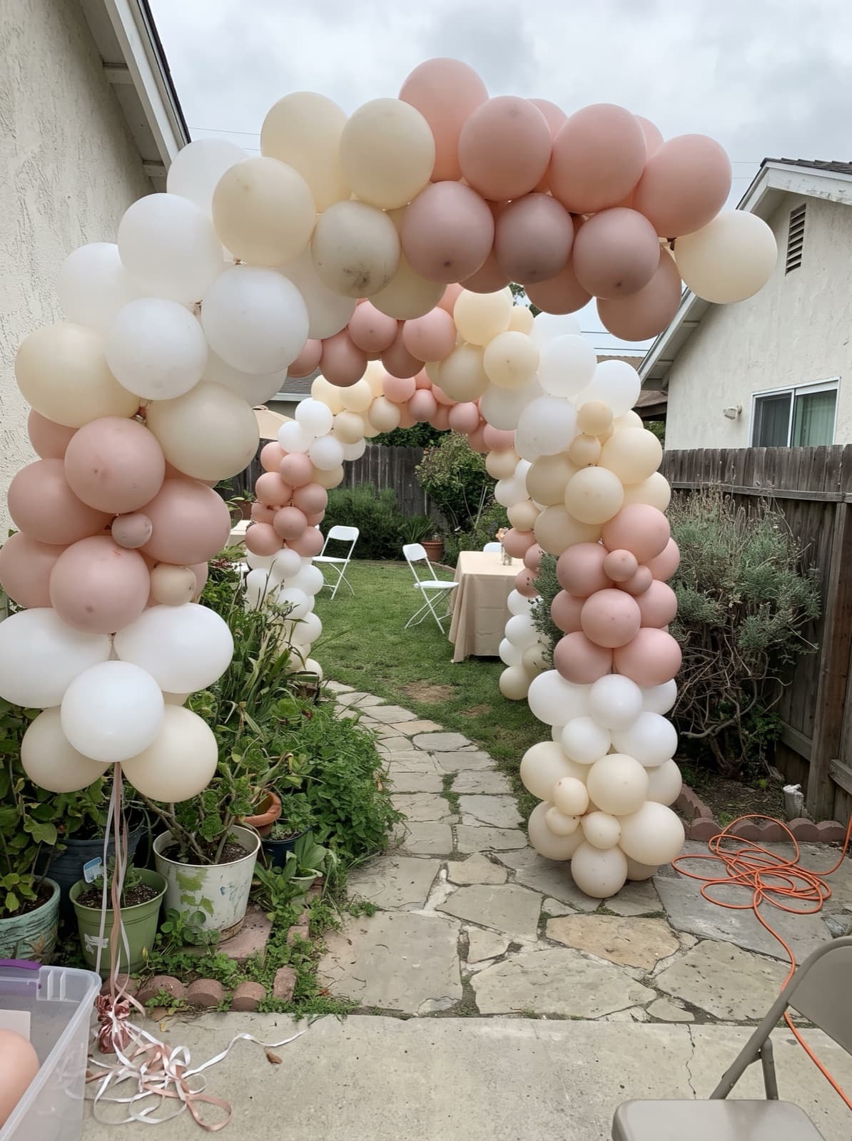 Blush and white balloon tunnel over a garden path