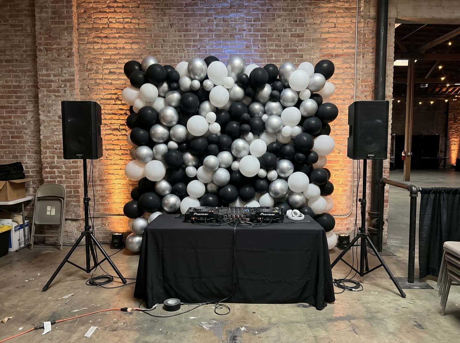 Black, silver and white balloon wall behind DJ speakers