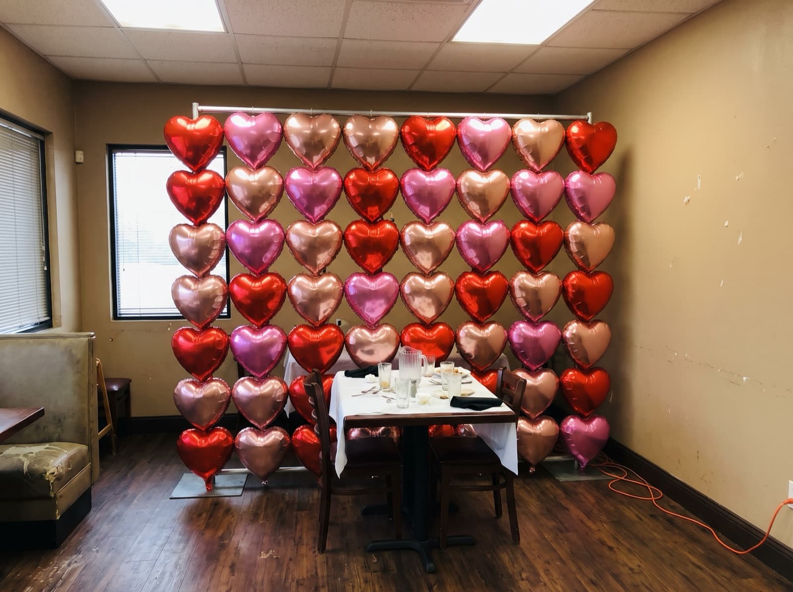 Rose gold, pink and red foil heart wall in a dining room