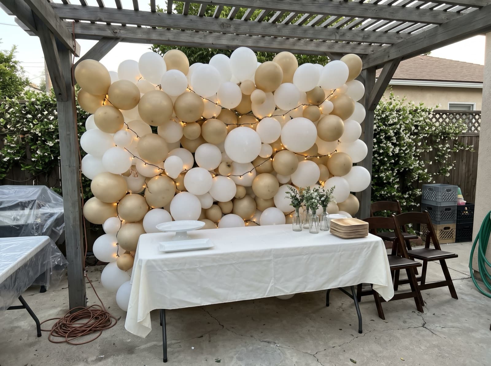 Champagne balloon wall woven with string lights under a pergola